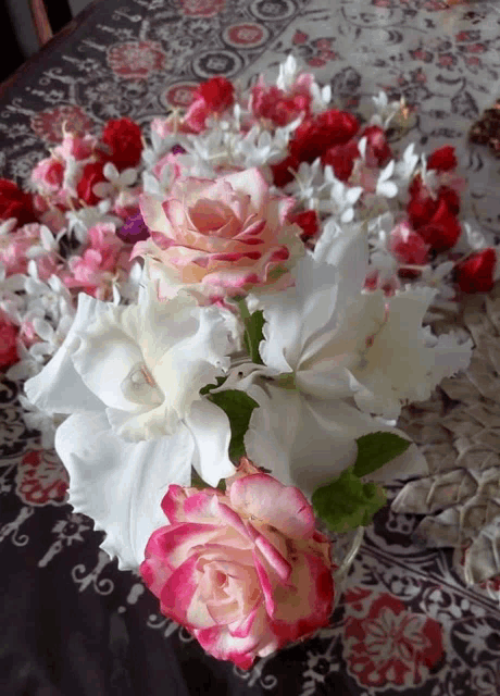 a bunch of pink and white roses on a table with petals