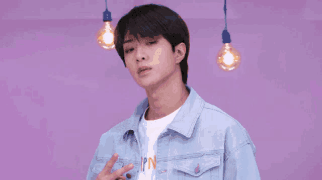 a young man wearing a denim jacket and a white shirt with the word pad on it