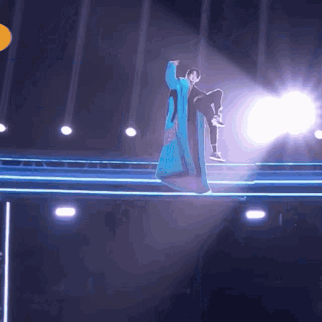 a person in a long blue coat is standing on a stage