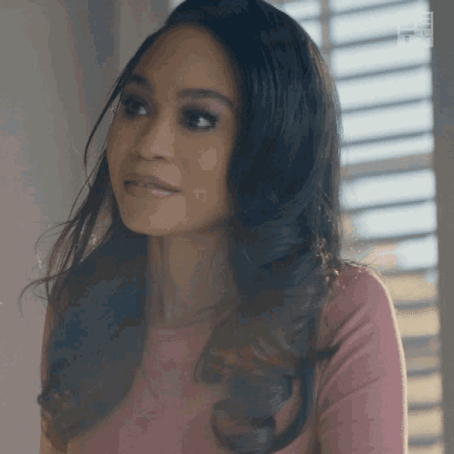 a woman in a pink shirt looks to the side