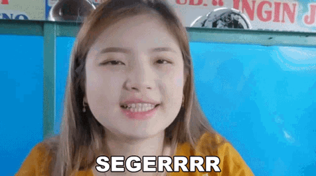 a woman with a yellow shirt is smiling and says segerrrr