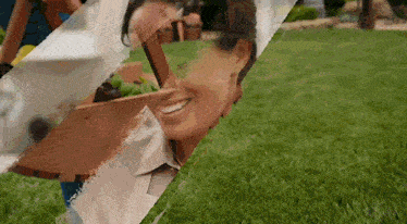a woman is smiling while holding a wooden box in a garden .
