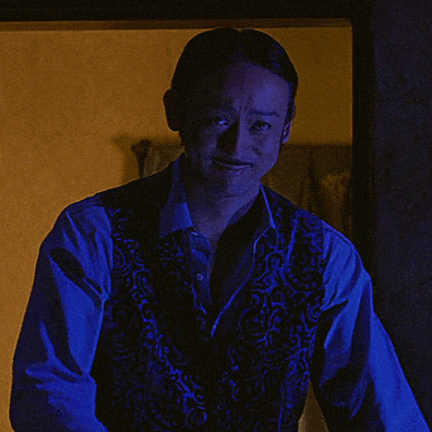 a man wearing a blue vest covering his face with his hand