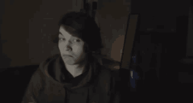 a young man is holding a piece of paper and a pen in a dark room .