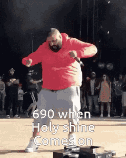 a man in a red hoodie is dancing on a stage while holding a microphone ..