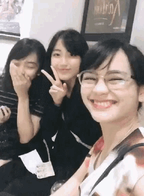 three girls are posing for a picture and one of them is wearing glasses and smiling