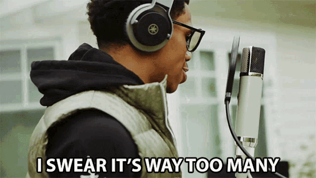 a man wearing headphones singing into a microphone with the words " i swear it 's way too many " below him