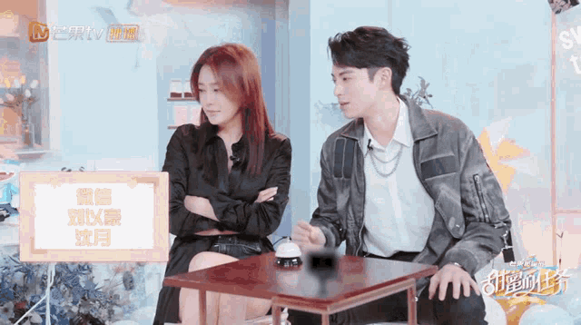 a man and a woman are sitting at a table in front of a sign that says ntv