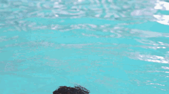 a man is swimming in a pool with water pouring out of his mouth