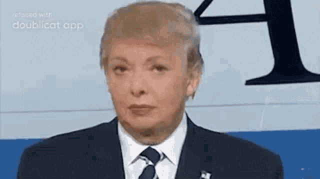donald trump is wearing a suit and tie and making a funny face while giving a speech .