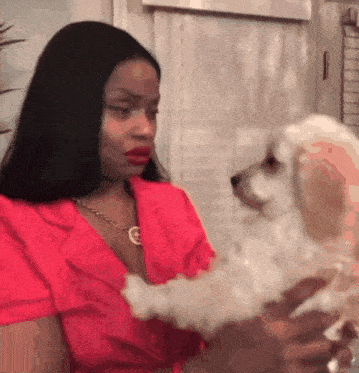 a woman is holding a small white dog in her arms