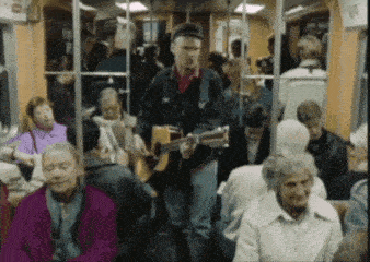 a man is playing a guitar in a crowded bus