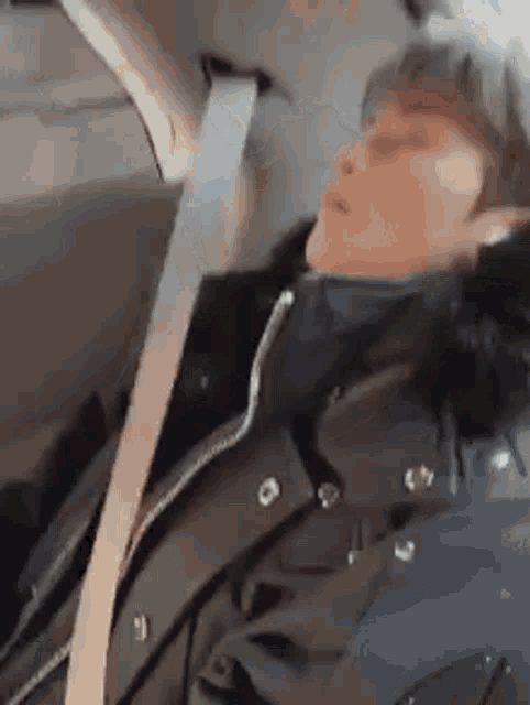 a man is sleeping in the back seat of a car with a seat belt .