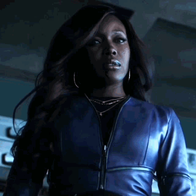 a woman in a blue leather jacket stands in front of a stack of cases
