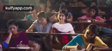 a group of people are sitting in a classroom with a girl sitting in the middle .