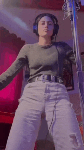 a woman wearing headphones is standing in front of a microphone .