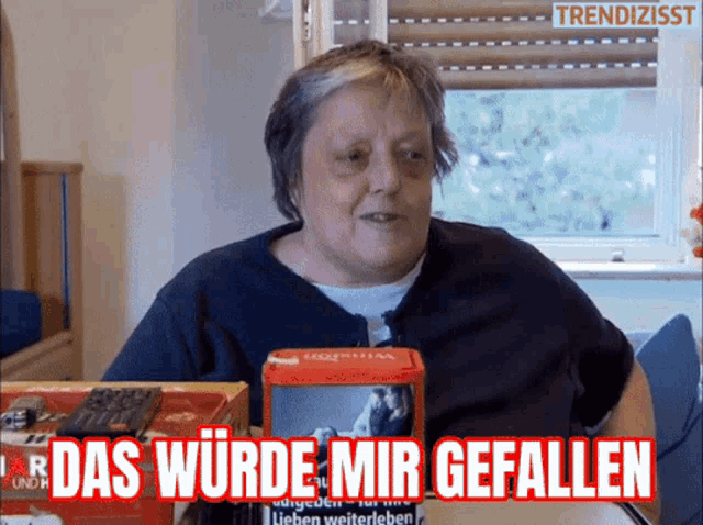 a woman is sitting at a table with a box that says das wurde mir gefallen in red letters