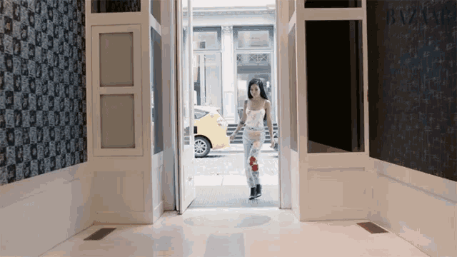 a woman walking through a hallway with a harper 's bazaar sign on the wall