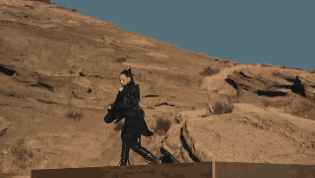 a woman singing into a microphone while standing in the desert
