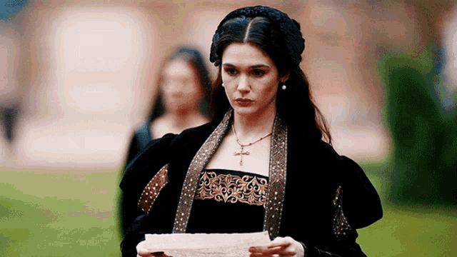 a woman in a black and gold dress is holding a piece of paper .