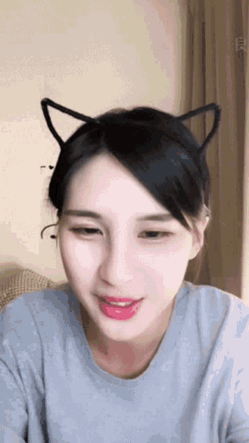 a woman wearing a cat ear headband is smiling and looking at the camera