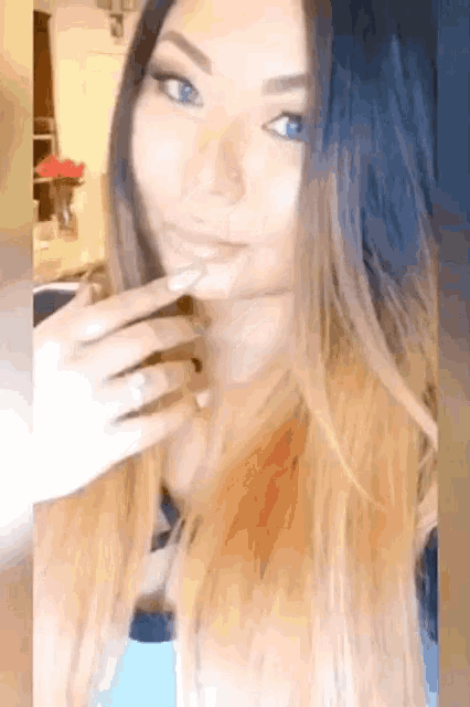 a woman with long hair and blue eyes is taking a picture of herself .