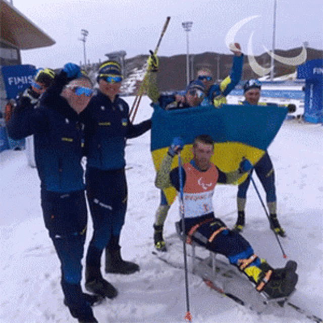 a group of skiers are posing for a picture in front of a blue finish sign