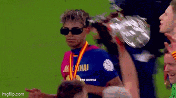 a soccer player wearing sunglasses is holding a trophy on his shoulder .