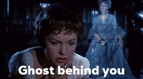 a woman in a white dress is looking at a ghost behind her in a movie .