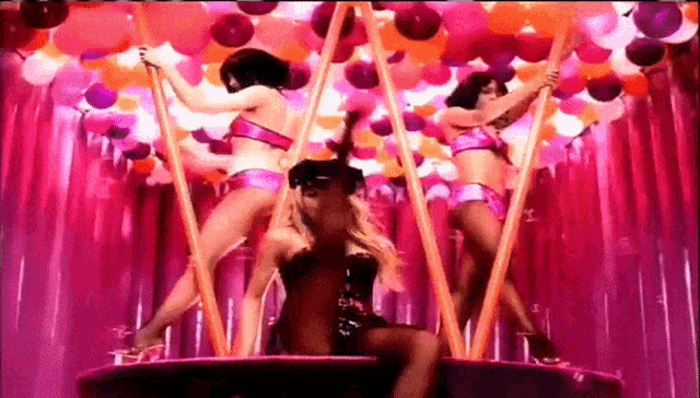 three women are dancing on poles in a room with balloons hanging from the ceiling