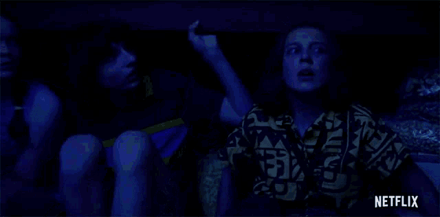 a man and a woman are sitting in a dark room with a netflix logo in the background .