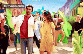 a man and a woman are dancing on a street with a crowd of people .