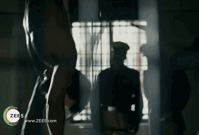 an ad for zee5 shows a man hanging upside down in a cell