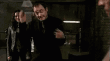 a man in a suit and tie is standing in a dark room with a woman in a leather jacket .