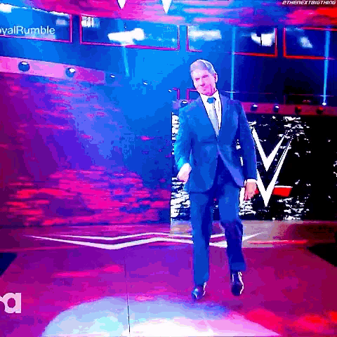 a man in a suit and tie is walking on a stage ..
