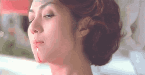 a close up of a woman 's face with blood dripping from her mouth