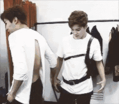 two men are standing next to each other in a room and one of them is wearing a shirt with a hole in the back