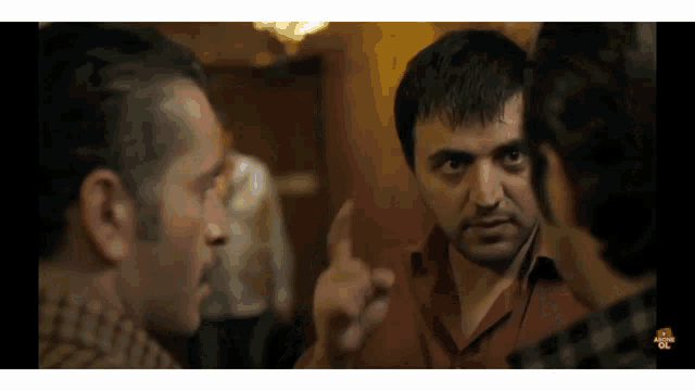 a group of men are having a conversation and one of them is pointing his finger