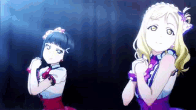 two anime girls are standing next to each other on a stage with their hands in the air .