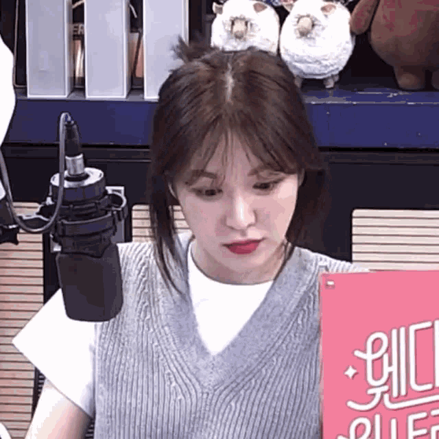 a woman is sitting in front of a microphone and holding a sign that says ' puff ' on it