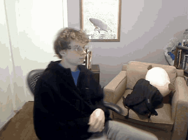 a man in a black jacket is sitting in a chair in front of a picture of a surfboard
