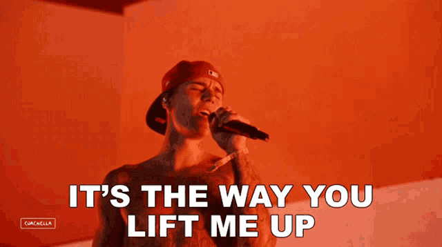 a man singing into a microphone with the words " it 's the way you lift me up "
