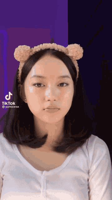 a girl wearing a headband with teddy bear ears has a tiktok icon on her face