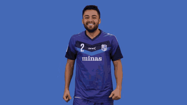 a man wearing a blue minas jersey holds his fist up in the air