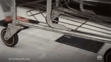 a person is pushing a cart with wheels on the floor .