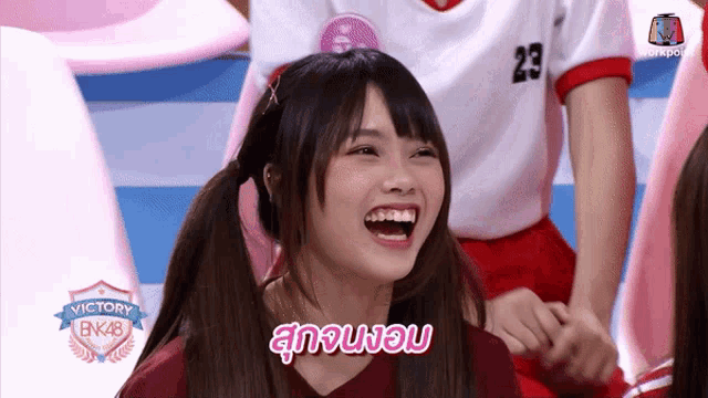 a girl in a victory bnk48 shirt smiles