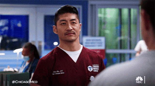 a man wearing a chicago medical center scrub talks to another man