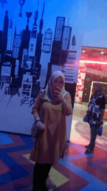 a woman taking a picture of herself in front of a wall with a picture of new york city on it