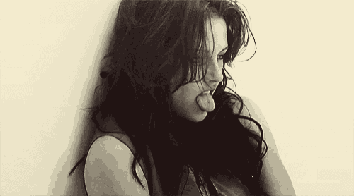a woman sticking her tongue out against a white wall