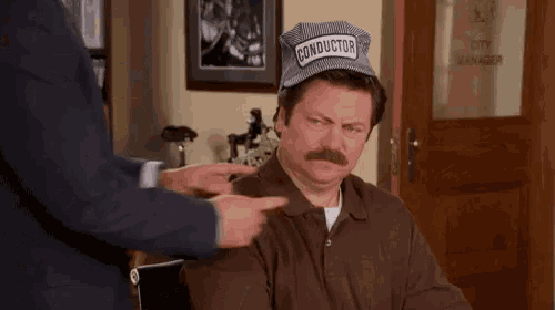 a man with a mustache wearing a hat that says conductor on it is being patted on the face .